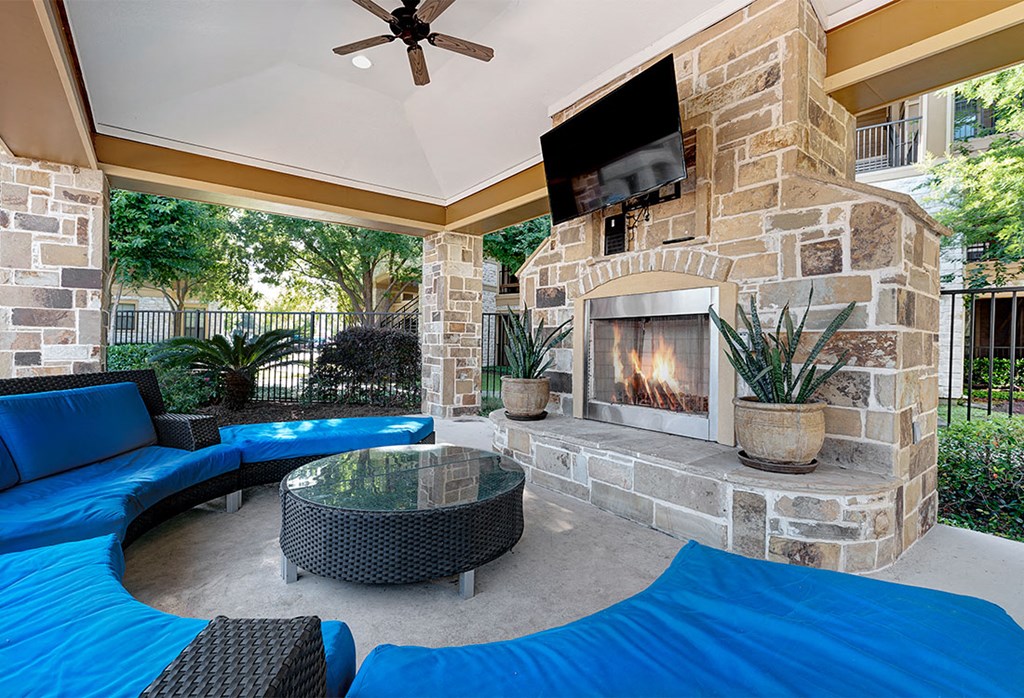 a covered patio with a fireplace and couches