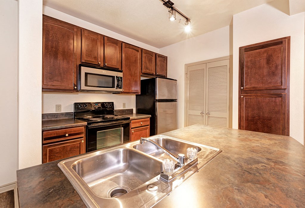 a kitchen with wooden cabinets and a stainless steel sink