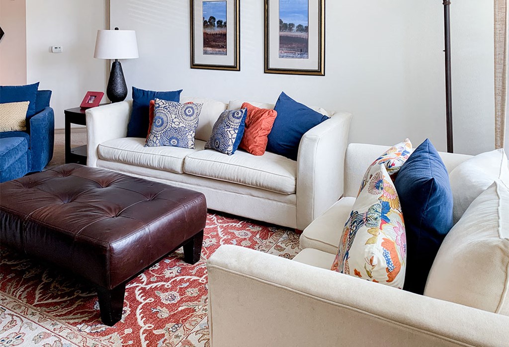 a living room with white furniture and a red rug