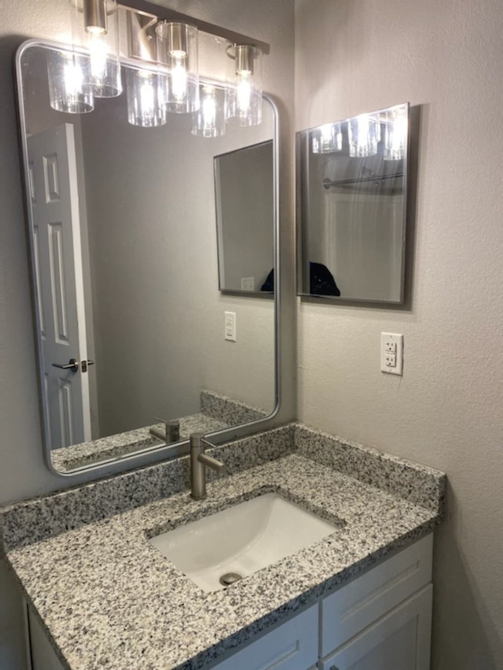 a bathroom sink with granite counter top and a mirror