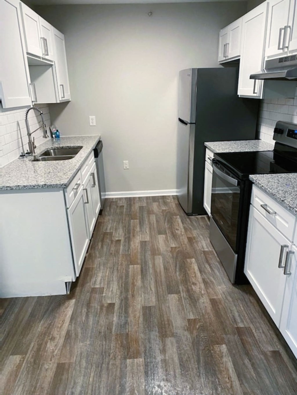 a renovated kitchen with a wooden floor and white cabinets