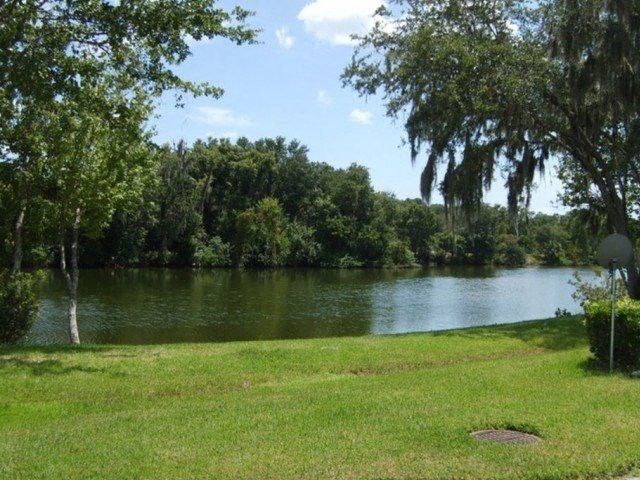 a grassy area with a lake in the background  at Waters Edge Apartments, Lakeland, FL, 33803