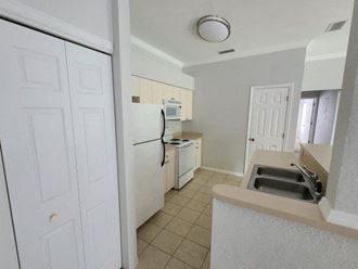 a kitchen with a white refrigerator freezer next to a sink