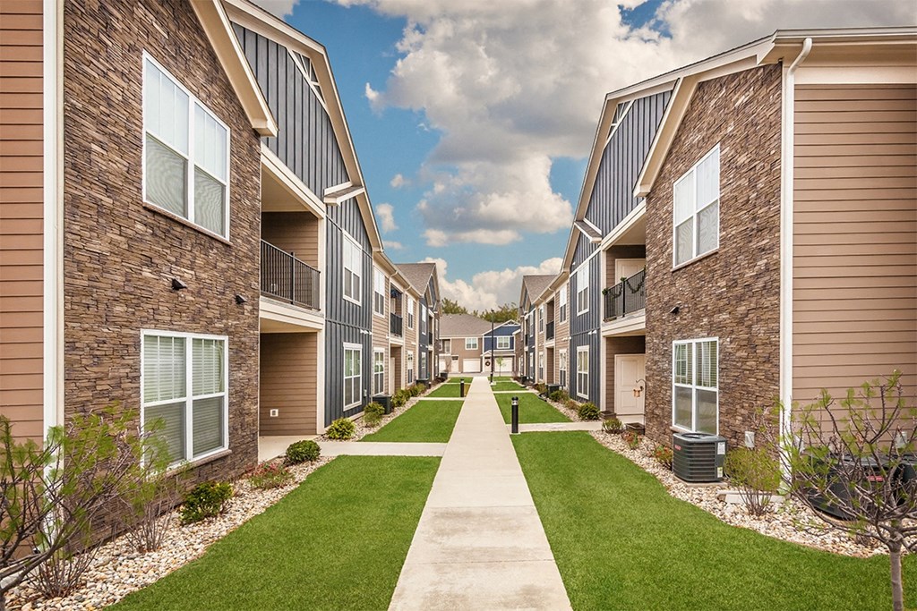 an exterior view of an apartment complex with a sidewalk and grassy area at Park 33, Goshen, IN