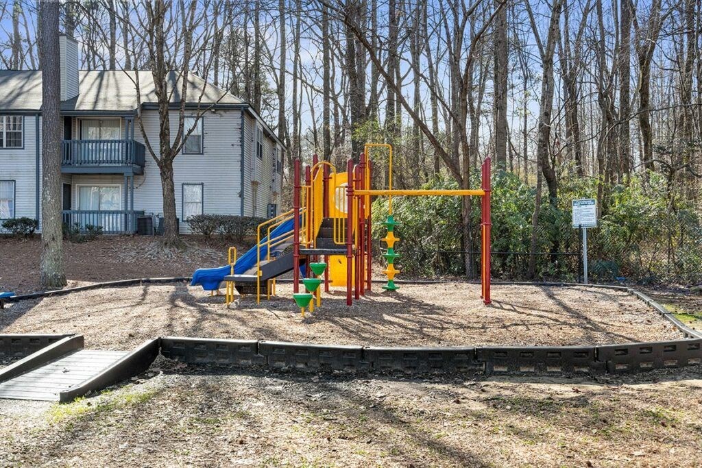 a playground with a swing set in front of a house
