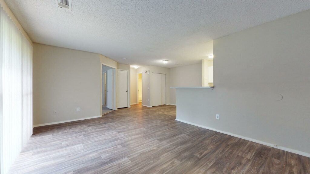 the living room and dining room of an empty house with wood flooring
