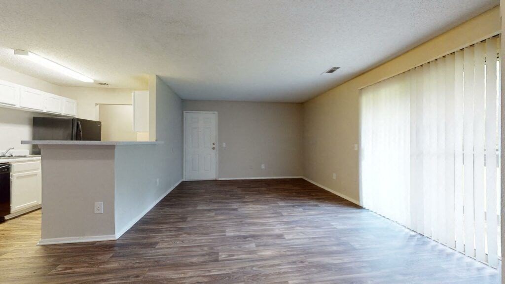 an empty living room and kitchen with wood flooring