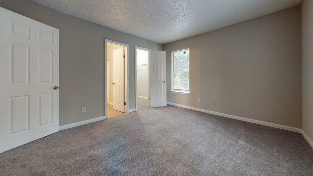 the living room of an empty house with a door to the hallway
