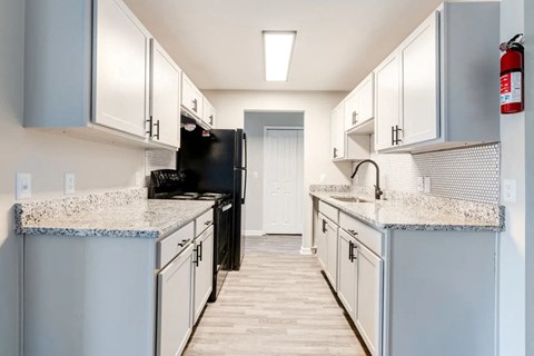 A kitchen with a black refrigerator and white cabinets.