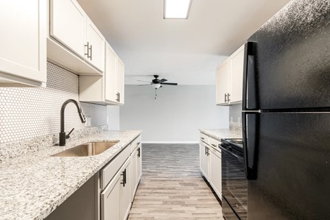 a kitchen with white cabinets and a black refrigerator