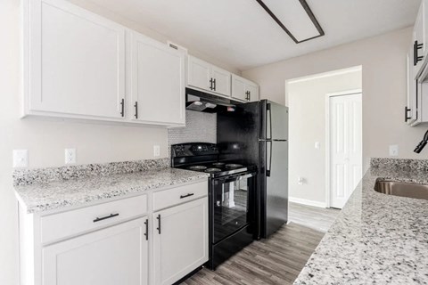 a kitchen with white cabinets and a black refrigerator