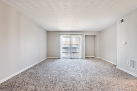A spacious room with a carpeted floor and a sliding glass door.