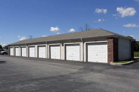 a row of garages with white doors and a brick building