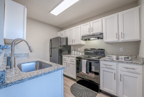 A kitchen with white cabinets and a granite countertop.