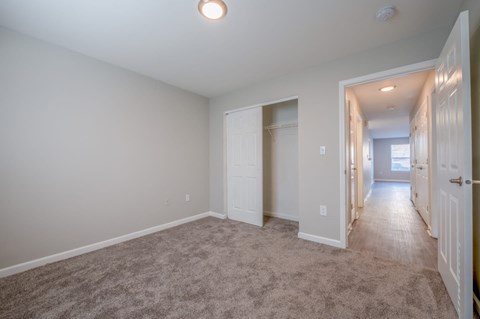 a room with a carpeted floor and a hallway with a closet