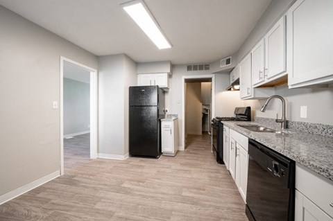 a kitchen with white cabinets and a black refrigerator