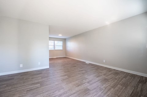 an empty living room with white walls and wood floors