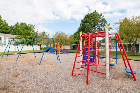 A playground with a red swing set and blue slide.