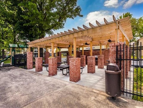 a patio with brick pillars and a wooden pavilion with tables