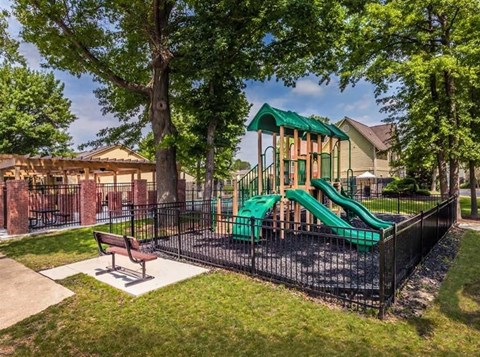 A playground with a green slide and a bench.