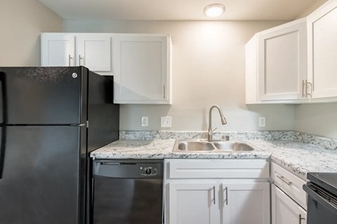 a kitchen with white cabinets and a black refrigerator