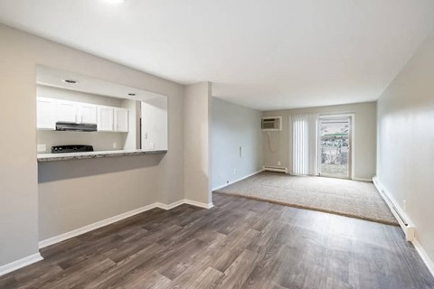 A spacious room with wooden flooring and a sliding glass door.