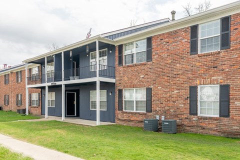 the front of a brick apartment building with a porch and a sidewalk