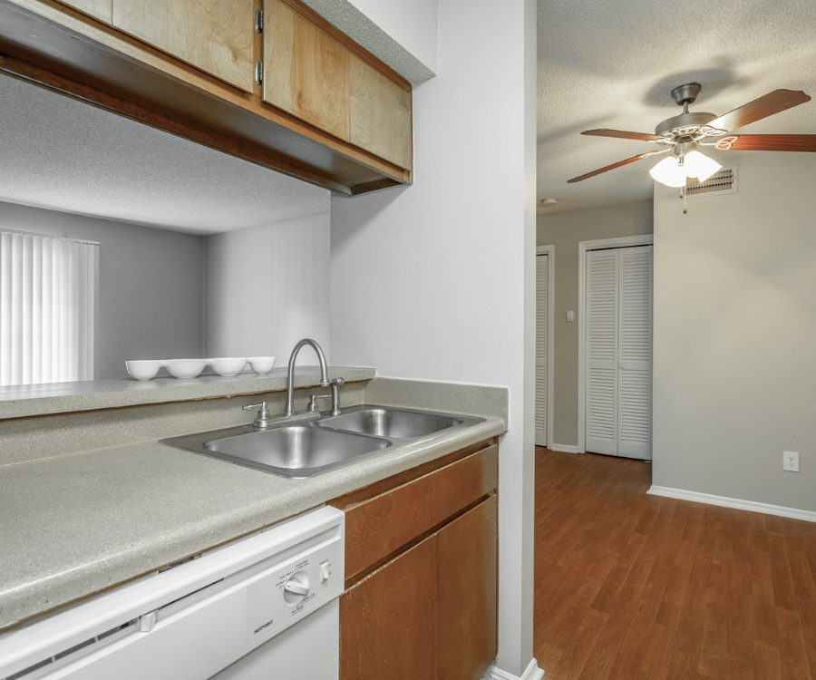 an empty kitchen with a sink and a ceiling fan