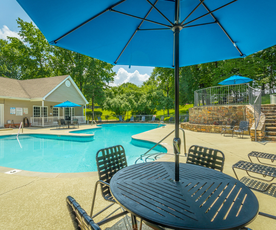 a swimming pool with a table and chairs under an umbrella