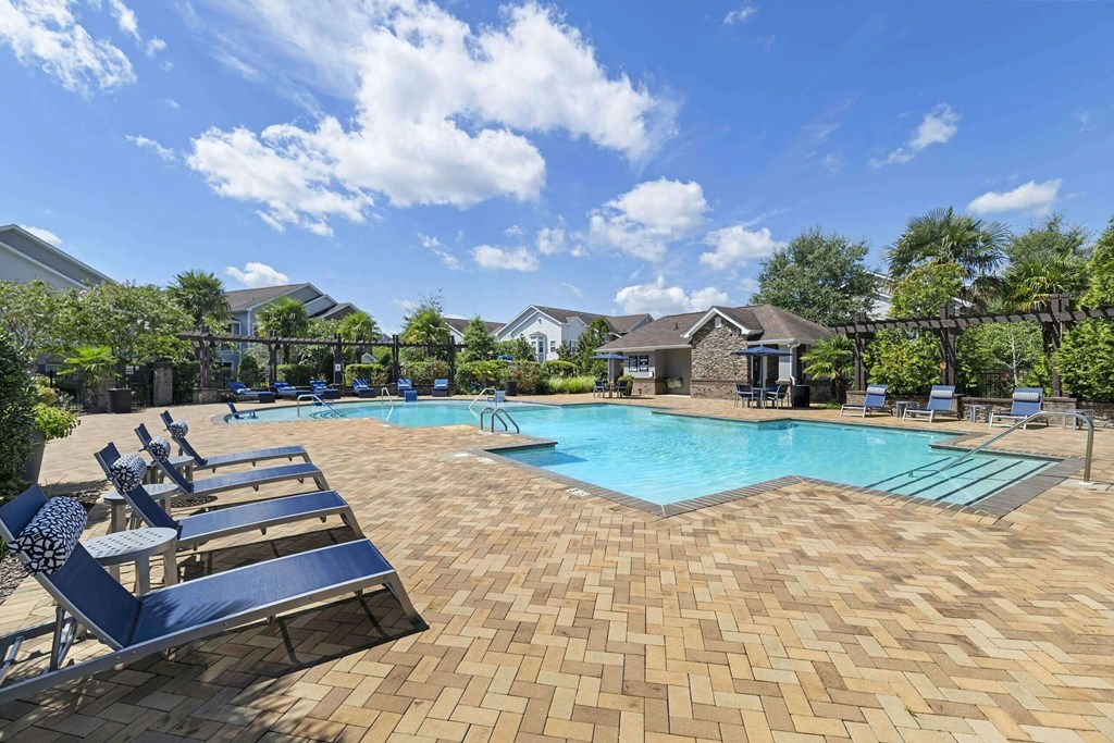 a resort style pool with blue lounge chairs around it at Century HomePlace, Prattville, AL
