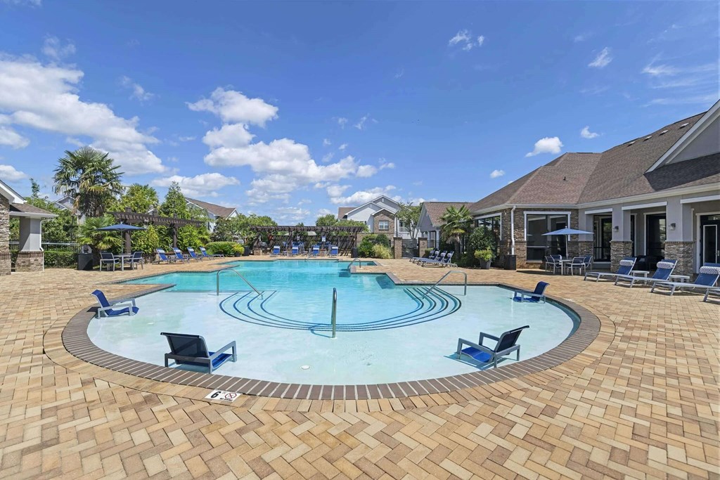a large swimming pool with chairs around it in front of a house at Century HomePlace, Prattville Alabama