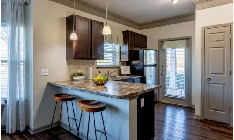 a kitchen with an island with stools and a refrigerator at Century HomePlace, Prattville