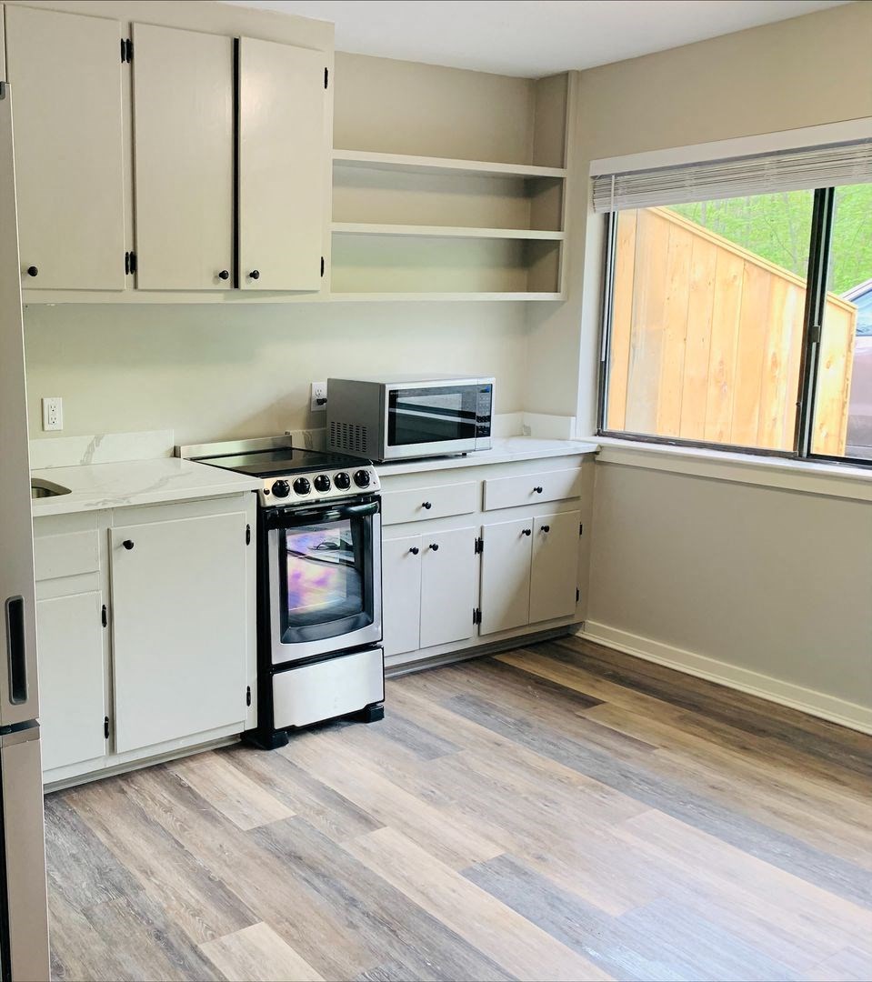 a kitchen with white cabinets and a stove and a window at Briarcliff at Quechee, Quechee, VT 05059