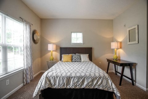 A bedroom with a patterned bedspread and two lamps on side tables.
