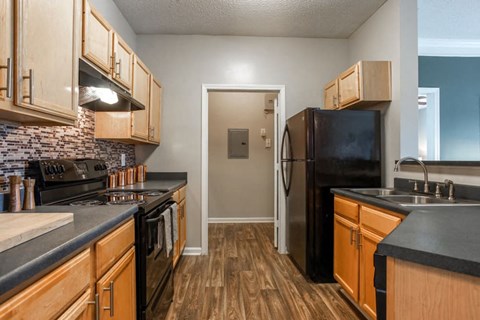 A kitchen with wooden cabinets and black countertops.