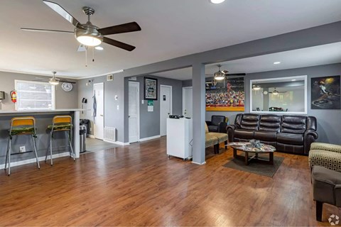 A living room with a black leather couch and a ceiling fan.