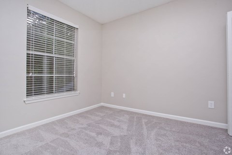 an empty room with a window and a carpeted floor