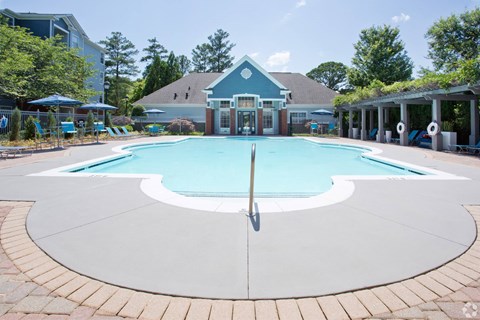 a large swimming pool with a house in the background