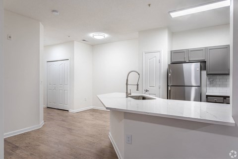 an empty kitchen with a large counter top and a stainless steel refrigerator