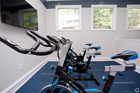 a gym with several exercise bikes and a tv