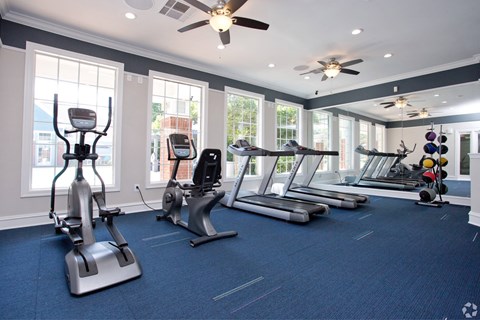 a gym with cardio equipment and windows