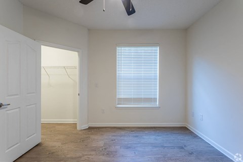 a bedroom with white walls and a window and a closet