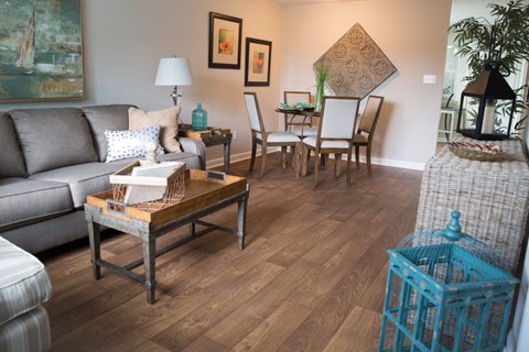 A living room with a grey couch, a wooden coffee table, and a dining table with chairs.