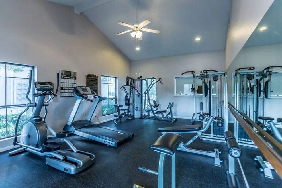 a gym with cardio machines and a ceiling fan