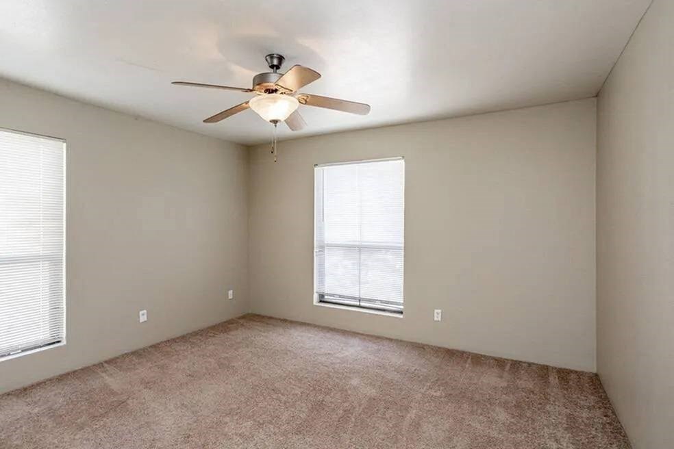 an empty living room with a ceiling fan and a window