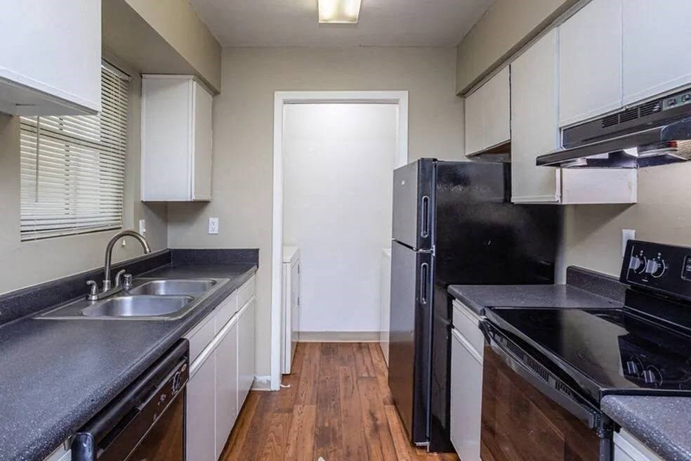 an empty kitchen with black appliances and white cabinets