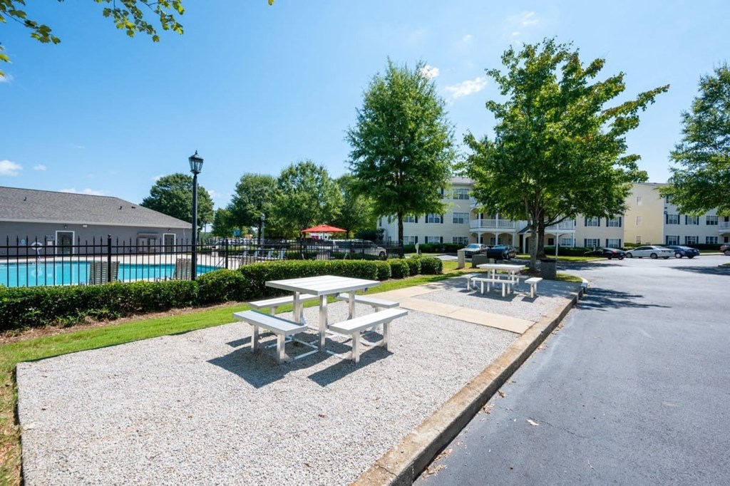 A sunny day at a picnic area with a pool in the background.