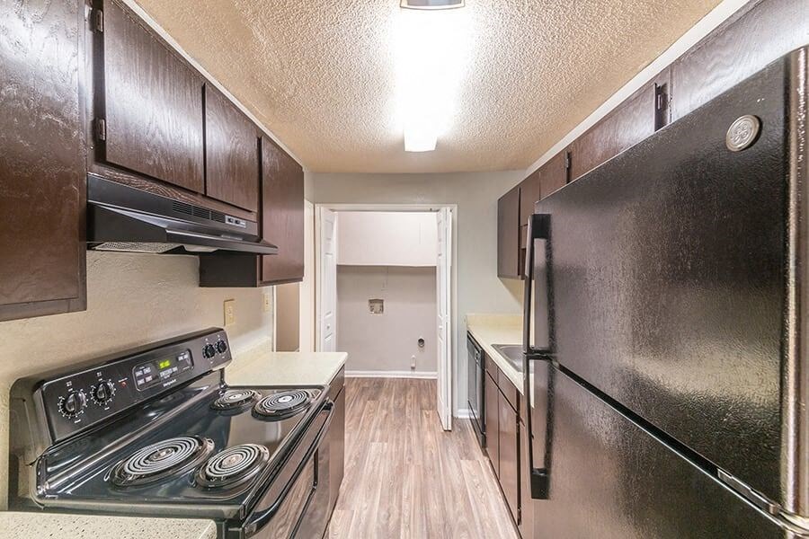 A kitchen with a black stove top oven and a black refrigerator.