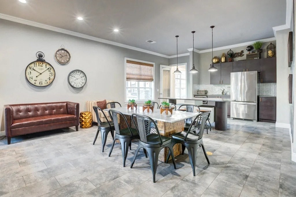 A modern dining room with a brown leather couch, a dining table set with plates, and three wall clocksat Century Ariva, Lakeland Florida  .