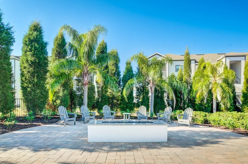 A patio with a white table surrounded by trees and chairs.at Century Ariva, Florida  